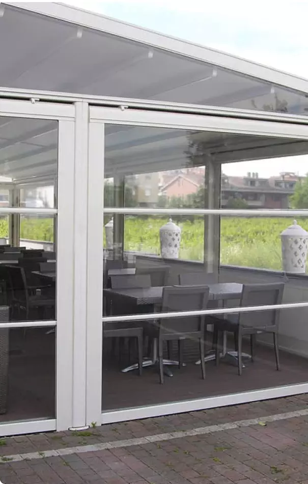 Vista interna di un ristorante con tavoli all'aperto, circondato da una vegetazione verde e arredi eleganti.