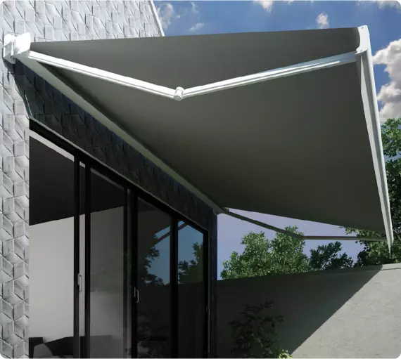 Tenda da sole moderna installata su un elegante edificio, con una struttura bianca e un grande telo grigio, che offre ombra su una vetrata. Sullo sfondo si vedono alberi verdi e un cielo parzialmente nuvoloso.